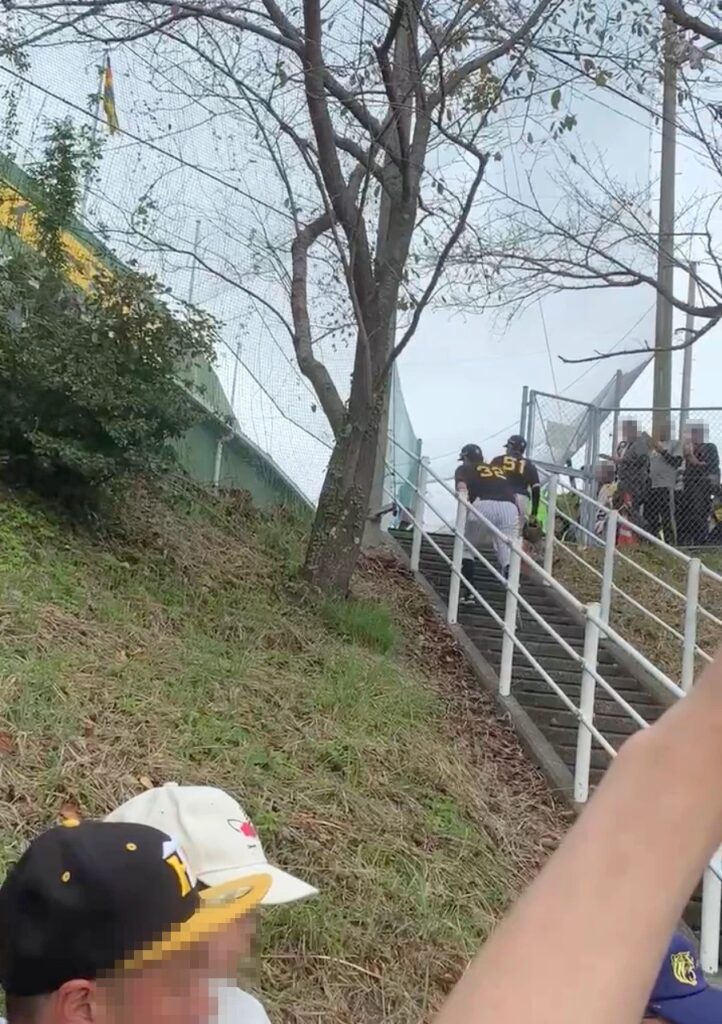 球場の階段を上って移動する選手たちと、柵の向こうで待つファン（お客さんの顔はモザイク）