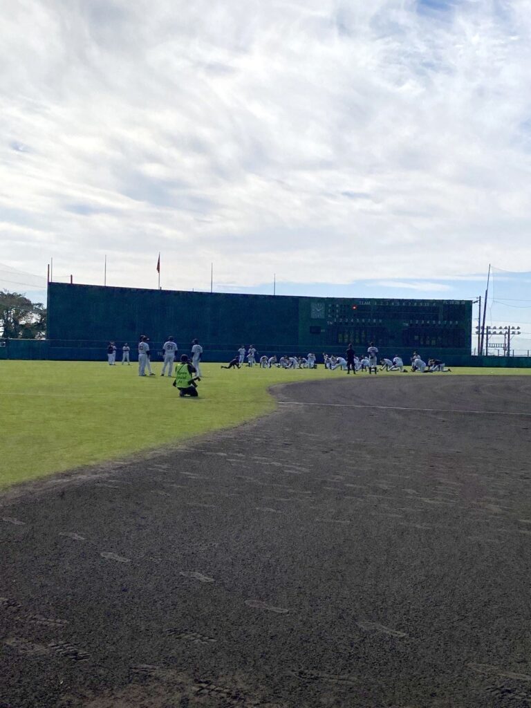安芸タイガース球場の外野で、選手たちが分かれてウォーミングアップをしている様子