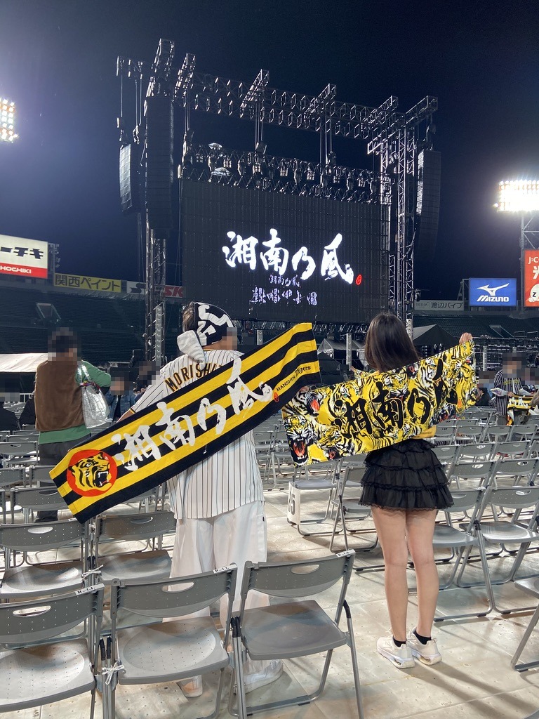 湘南乃風の甲子園ライブで、グラウンドの客席から湘南乃風のタオルとはっぴを広げる後ろ姿