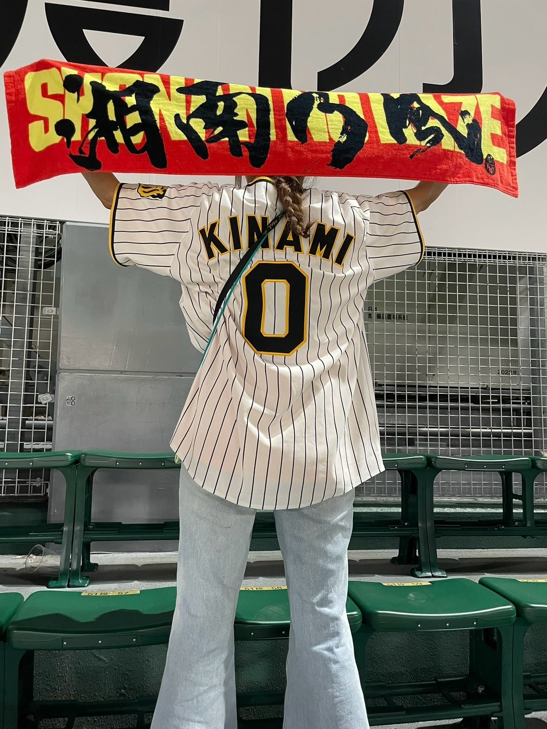 甲子園の座席の前で、湘南乃風のタオルを広げる木浪選手の背番号0のユニフォームを着た後ろ姿